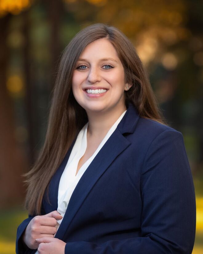 female businesswoman in blue jacket and white top smiles for outdoor fall foliage portrait