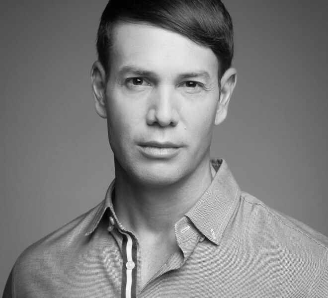black and white male actor with a serious look on a plain background and a button up shirt