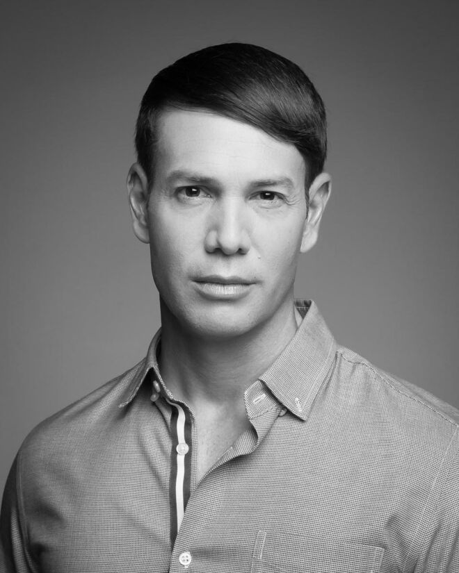 black and white male actor with a serious look on a plain background and a button up shirt