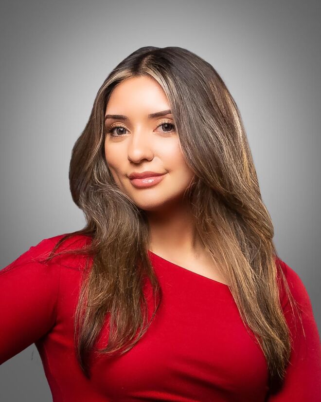 Pretty female realtor in red dress smiling on a grey background