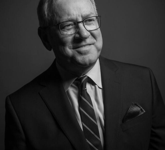 black and white portrait headshot of a University of Oklahoma surgeon, smiling of camera, wearing a dark suit and tie