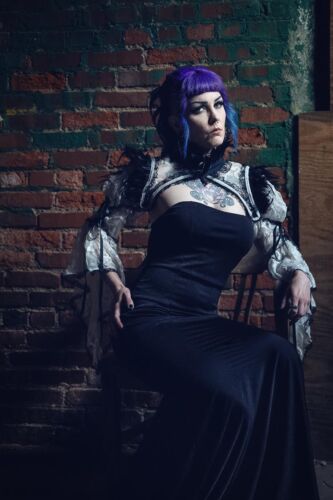 Gothic model in grungy warehouse wearing black dress with purple hair