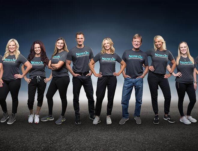 team composite photo of orthodontist office staff standing on a concrete floor that fades off into a blue background