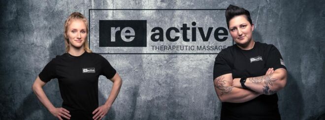 Two woman business teammate pose in front of their logo branded wall