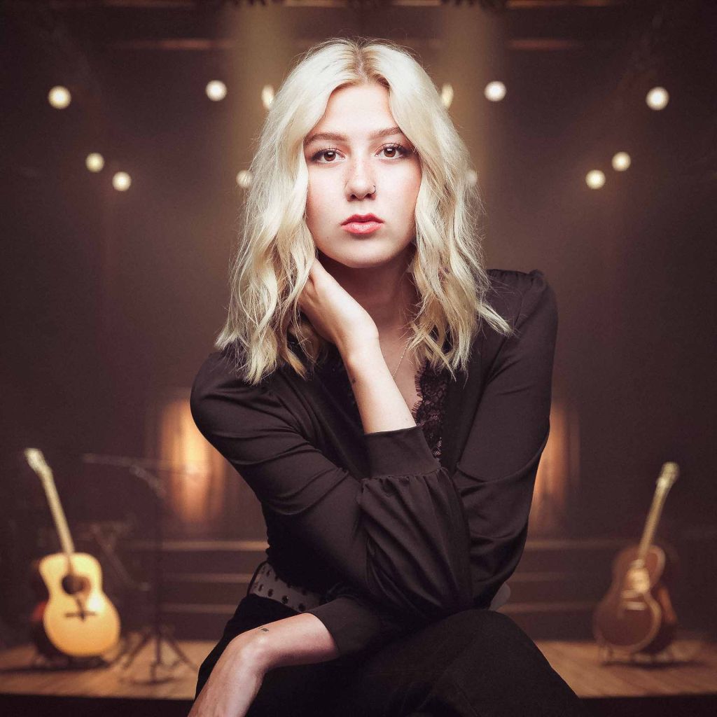pretty blonde musician sitting on a stool in a music studio for her headshot in Tulsa