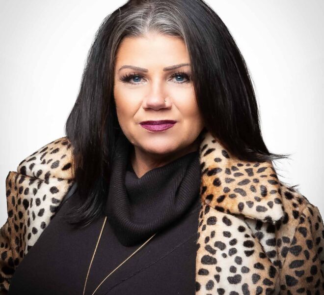 Beautiful businesswoman in a black top with black hair and blue eyes, wearing a leapord print coat, smiling on a white background