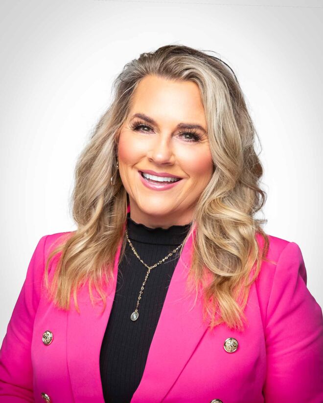 Pretty blonde businesswoman in a black sweater and pink coat, laughs and smiles on a white background during