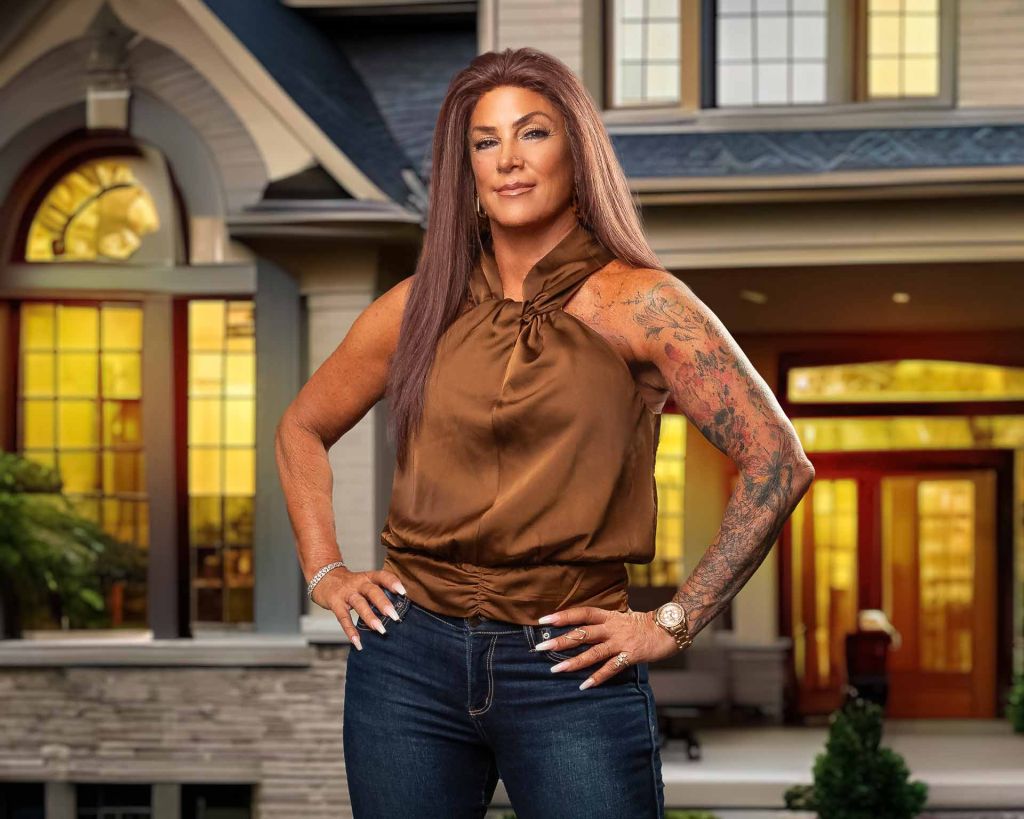 realtor posing for headshot photo in front of a house. she is wearing a sleeveless top and jeans. Tulsa Headshot Photography Portfolio