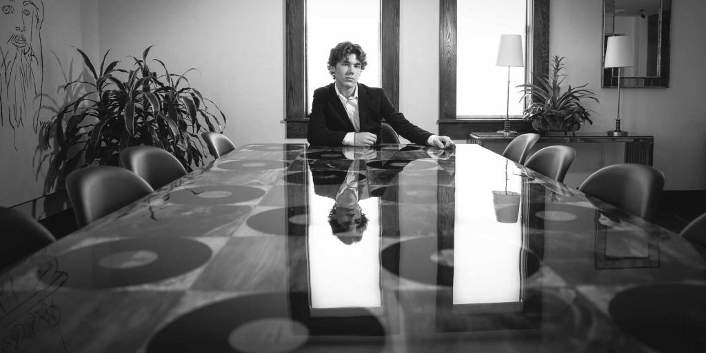 young man sitting at the end of a table full of records at The Church recording studio