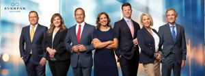 Corporate team smiling and standing in front of digital blue background