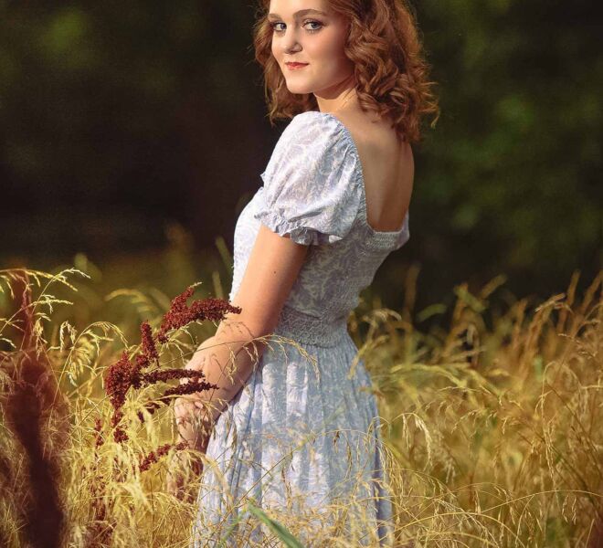 young woman in a vintage dress in a field of tall grass