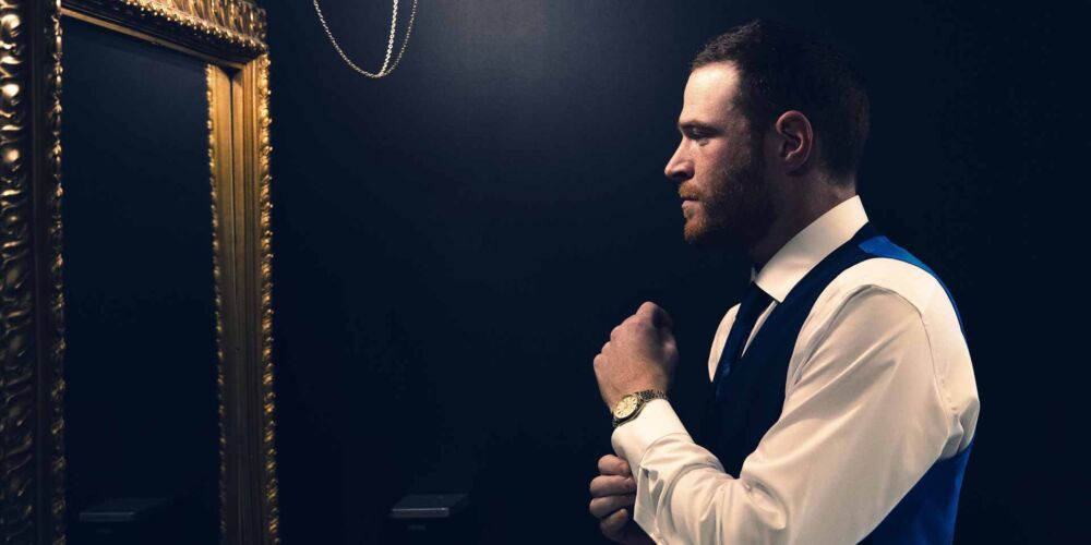 Groom getting ready in the mirror for his wedding day - cinematic video production in Tulsa