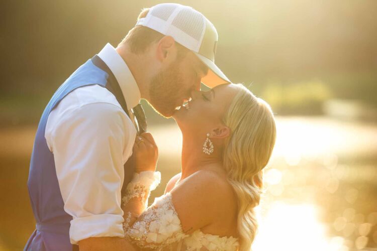 beautiful young couple kissing at sunset with golden haze over a lake