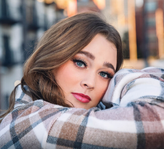 beautiful blue eyed young woman leans on a concrete pillar while posing for photos in downtown Tulsa