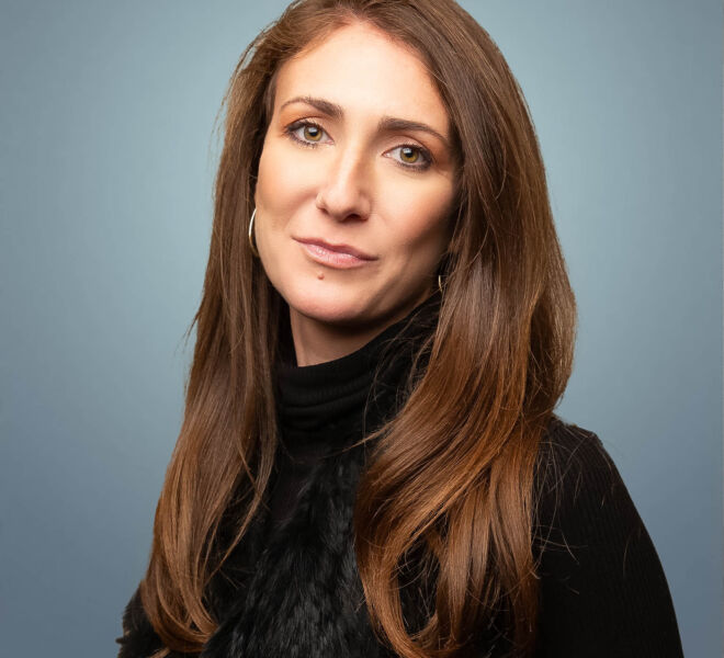 Pretty female lawyer in a black vest posing for headshots on a blue background