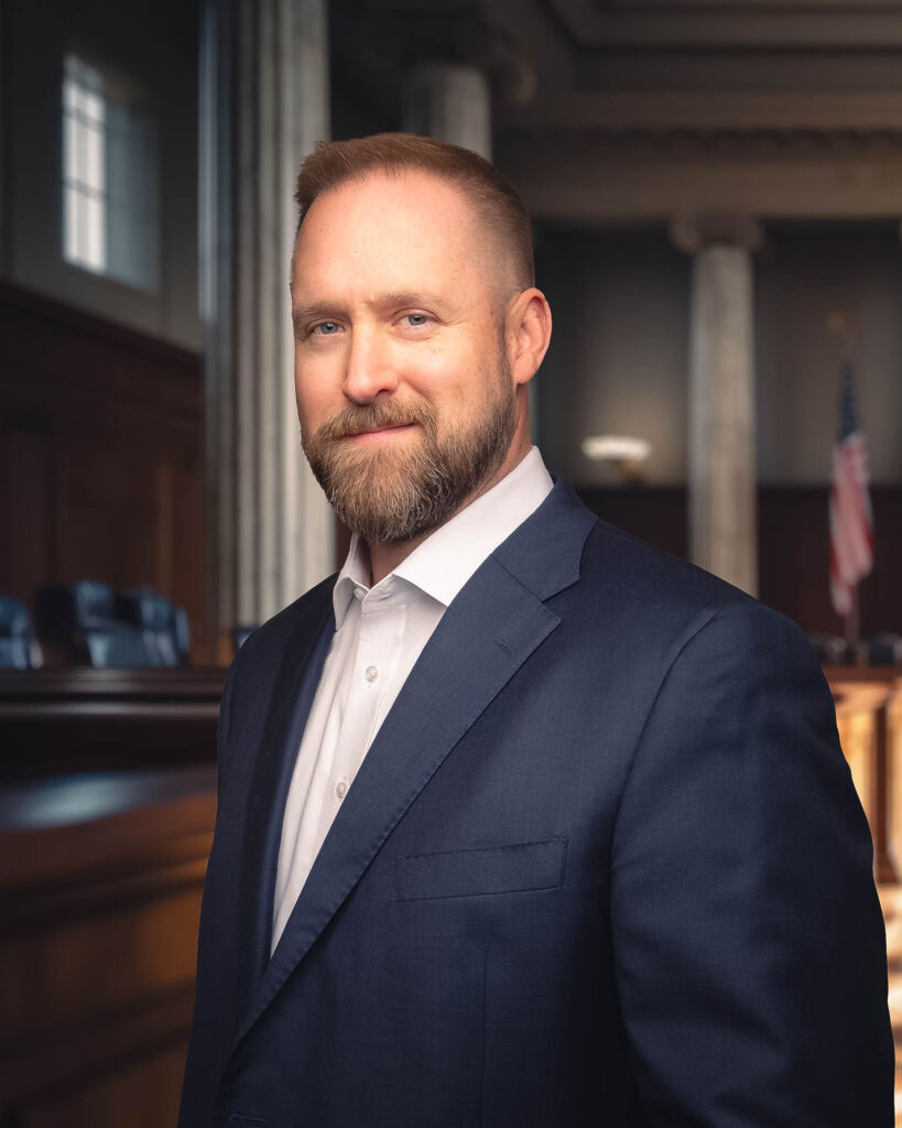 Tulsa attorney in a suit with no tie, smiling in a courtroom
