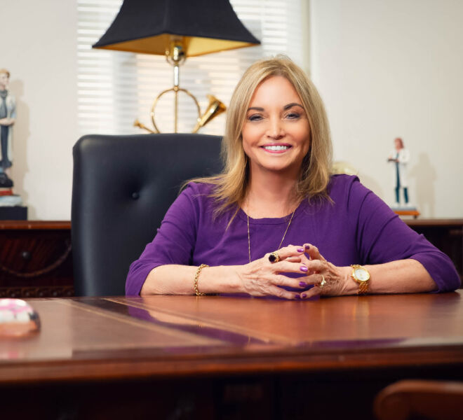 Happy female doctor sitting at her desk, smiling, wearing a purple dress