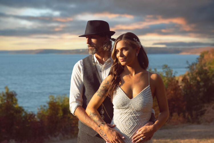 newly married couple smiling by the lake at sunset
