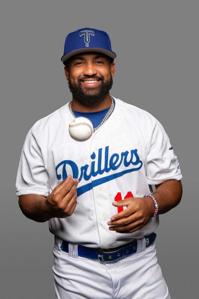 tulsa drillers baseball player tossing a ball and smiling for his headshot photo on a grey background