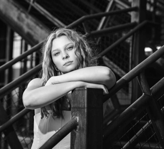 black and white of a young woman leaning on a stair rail