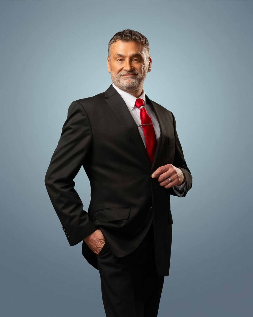 handsome male Tulsa realtor in a dark suit with red tie on a light blue background - commercial photography headshot