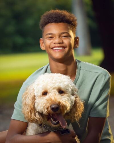 smiling boy holding his smiling dog at the park for a pet portrait