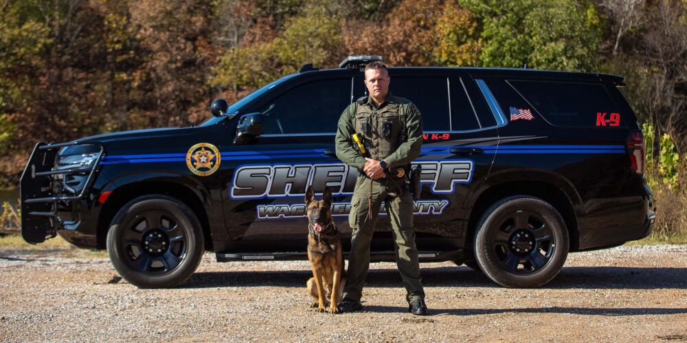 Police dog and his handler pose in front of police cruiser for team photo