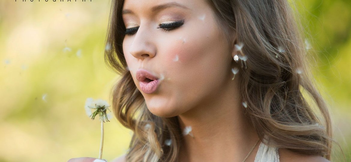 natural light senior portrait of a girl blowing a dandelion