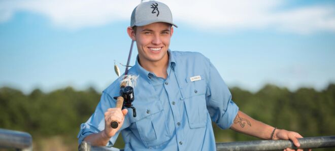 handsome young man smiling with a fishing pole