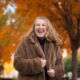 laughing girl in a fur coat with fall colors behind her