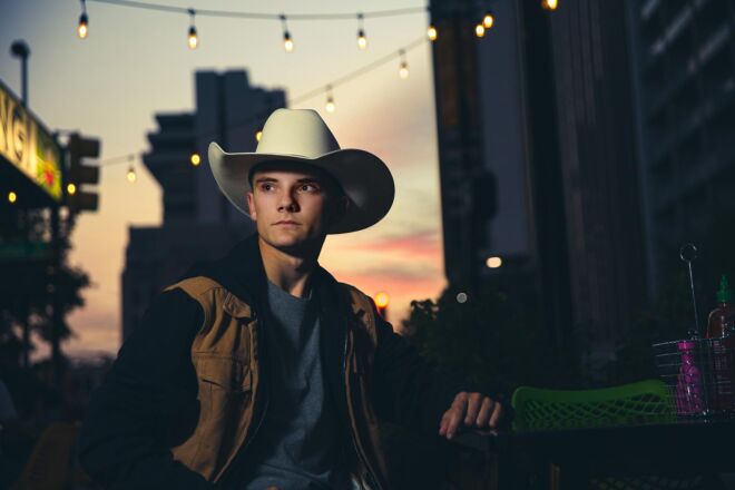young man in a cowboy hat downtown at dusk