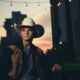 young man in a cowboy hat downtown at dusk