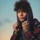 handsome young man poses in hoodie with championship rings for his senior pictures in Bixby