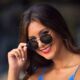 beautiful young woman looks over her sunglasses with a smile in downtown Tulsa