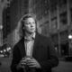 young man in sports coat holding a football downtown black and white