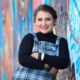 senior girl downton in a turtleneck on a colorful wall