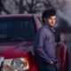 young man leaning on his truck at dusk on a country road