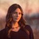 Young woman in golden hour sunset light outdoors by the river with black sweater