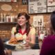 waitress serving a hamburger to diner patrons at hard rock tulsa commercial photography