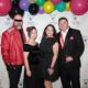 Themed party guests posing on logo background posed event photography in Tulsa