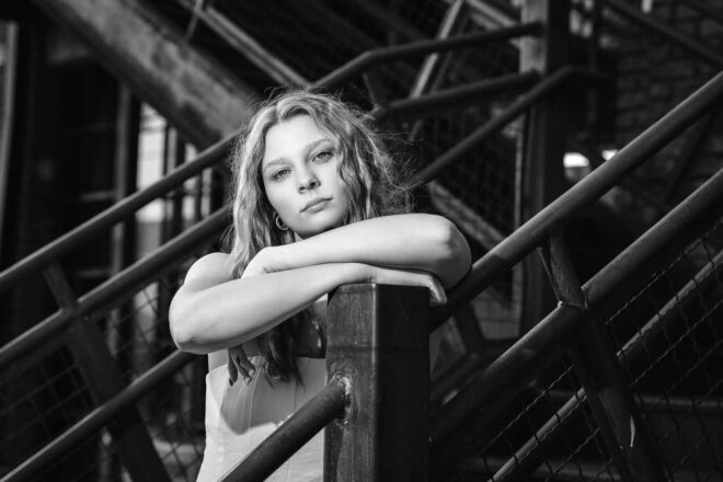 black and white of a young woman leaning on a stair rail