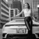 Young woman leaning on the back of a car