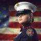 young woman in ROTC uniform in front of US flag