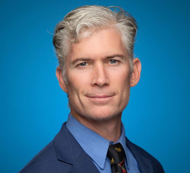 handsome man wearing a blue suit on a blue background, smiling for photo